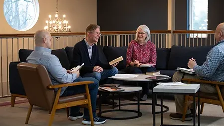 Pastor holding Bible sitting with three other church leaders.